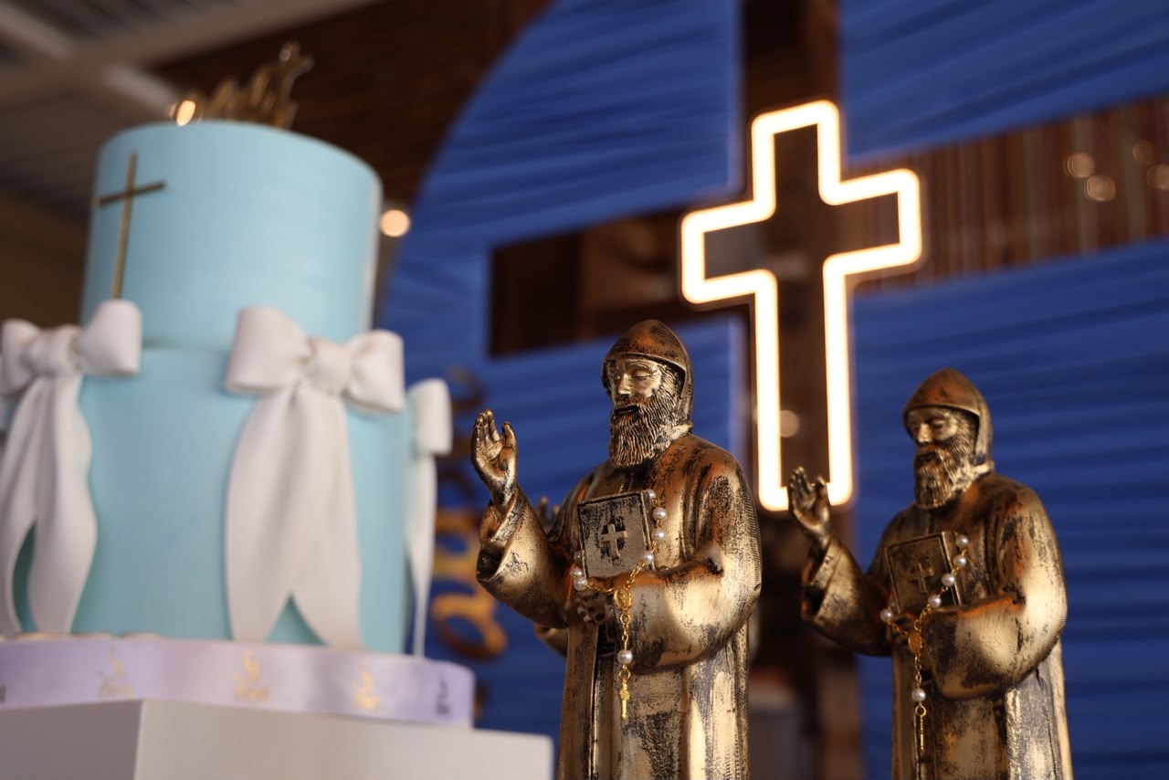 Baptism cake in pale blue beside a lit cross and gilded figures